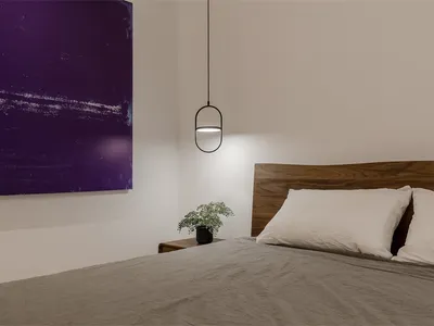 A minimalist bedroom with a wooden headboard and a purple abstract painting on the wall.