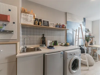 Modern minimalist residential kitchen with white countertops and stainless steel appliances.