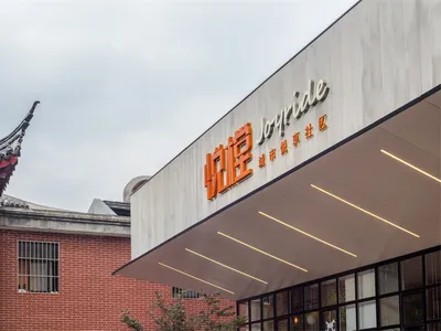 Modern restaurant exterior made of concrete with large windows and a sign reading "Joyride"