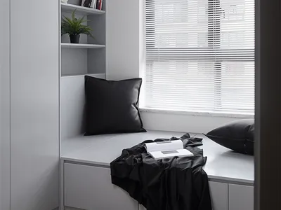 Modern minimalist bedroom with grey blinds and black pillows.