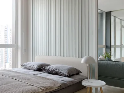 Modern minimalist bedroom with a neutral color palette, including a bed with a white headboard and grey linens, a white side
