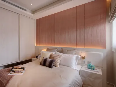 A minimalist bedroom featuring a white bed with a wooden headboard and white furniture.