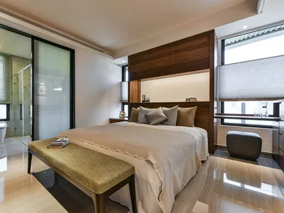 A modern minimalist bedroom featuring a white wood bed, glass panel wall, and sleek design.