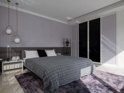 Minimalist bedroom, featuring a gray textile bedspread, modern lighting, and a wooden headboard, with a carpet, a potted plan