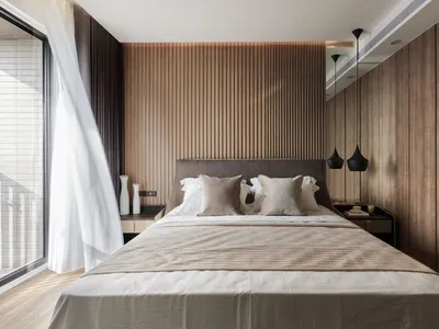 A modern minimalist bedroom featuring wood paneling and a comfortable bed with multiple pillows.