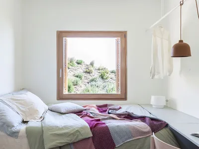 Bedroom with minimalist design, wooden furniture, and colorful fabric blanket