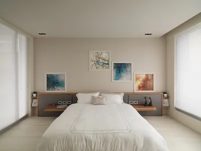 現代簡約臥室，配有白色床鋪、白色寢具，以及牆上的抽象畫作。
