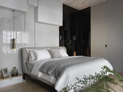 A modern minimalist bedroom with a white marble accent wall, metal headboard, and a grey bedspread.