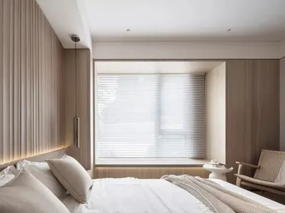 A minimalist bedroom featuring wood walls and a window with white blinds.