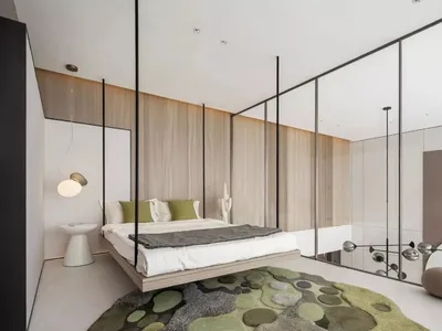 Modern minimalist bedroom featuring a floating bed, green accent pillows, and a green and gray rug with abstract circular pat