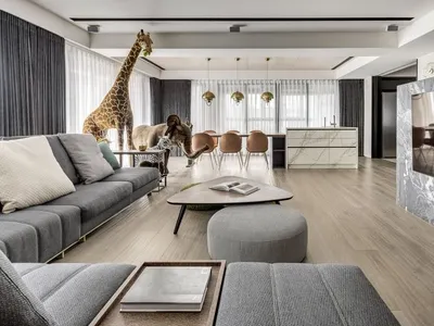 Modern living room featuring a dark grey sectional sofa, a round coffee table, a marble kitchen counter, and a large flat-scr