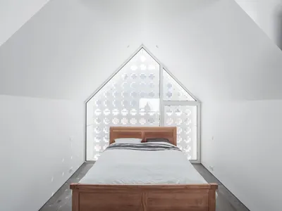 Modern minimalist bedroom with a wooden bed and geometric window