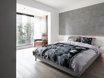 一間現代簡約臥室，擁有混凝土特色牆，以及一張鋪著黑白格紋被子的床，背景為