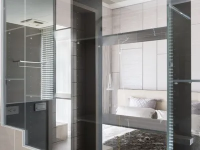 Modern minimalist bedroom featuring glass walls and a white bed.
