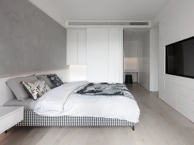 Modern minimalist bedroom with a built-in bed, sleek white cabinets, and wooden flooring.