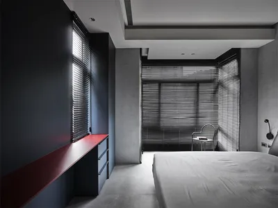 Minimalist bedroom with black blinds, white sheets, and concrete walls