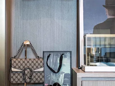 A luxury retail display featuring a Gucci purse, loafers, and a framed picture on a wooden dresser.