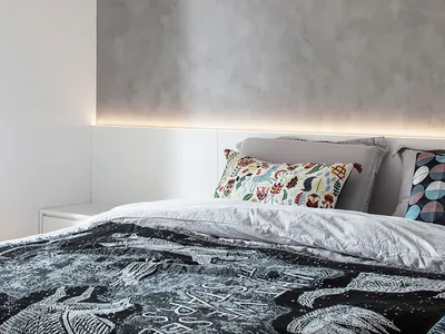 A stylish, minimalist bedroom featuring a bedspread with an abstract dragon design and patterned pillows.