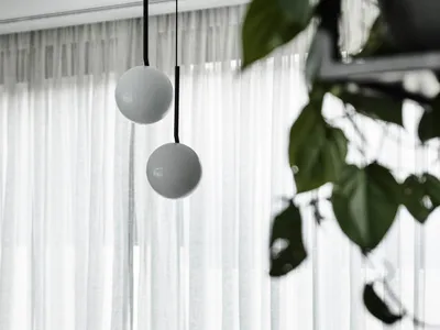 Modern kitchen with black and white marble countertops, black sink, and hanging white globe lights. White sheer curtains and
