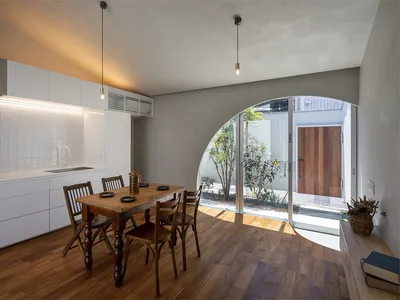 A minimalist residential kitchen with wooden elements and a view of the courtyard.