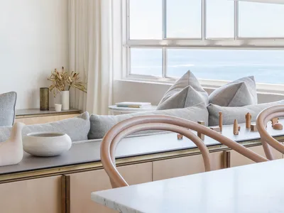 Modern kitchen featuring a marble countertop and wooden furniture with a view of the sea.
