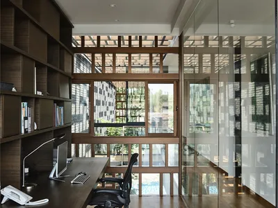 A modern home office featuring wooden furniture and large windows.