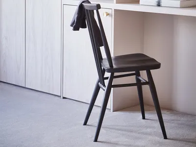 A modern home office featuring wooden furniture, including a chair, shelving unit, and cabinet.