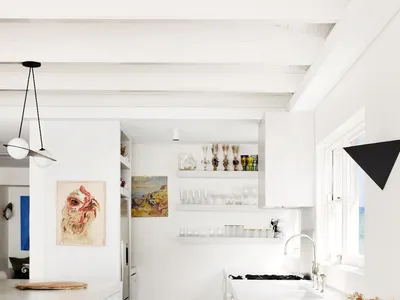 A modern minimalist kitchen with white cabinetry, white countertops, and wooden floor.