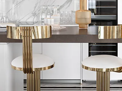 Modern kitchen featuring a marble countertop and golden bar stools.