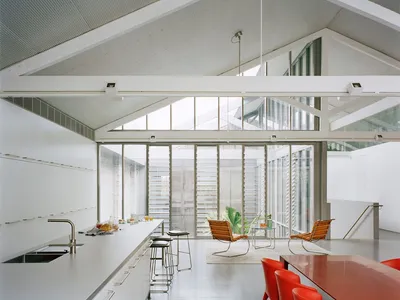 Modern minimalist kitchen with metal cabinets, glass walls, and red wooden tables