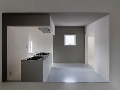 Modern minimalist kitchen with concrete island and floor, white walls, and gray accents.
