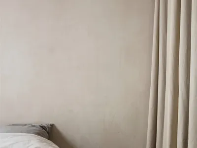 A minimalist bedroom with neutral tones and a bed.