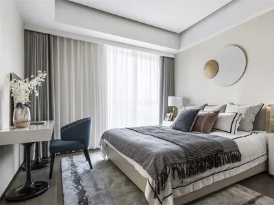 A modern bedroom featuring a brown couch, white flowers, and white curtains.