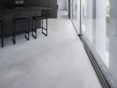 Modern, minimalist kitchen with concrete flooring and black furniture.
