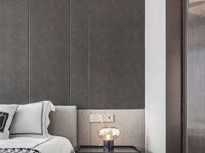 A minimalist bedroom with a bed, nightstand, and lamp, featuring gray fabric, glass, and metal materials.