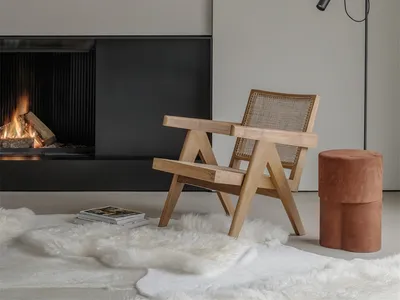 A minimalist interior design featuring a wooden armchair on a fur rug, a fireplace, and a modern floor lamp in a living room.
