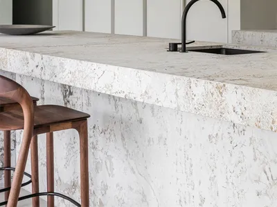 Modern, minimalist kitchen bar counter featuring a marble countertop and sleek black faucet.