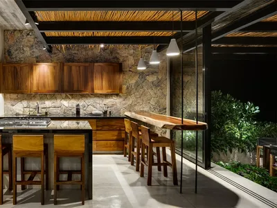 Contemporary residential kitchen with wooden cabinets and countertops, stone backsplash, and seating area.