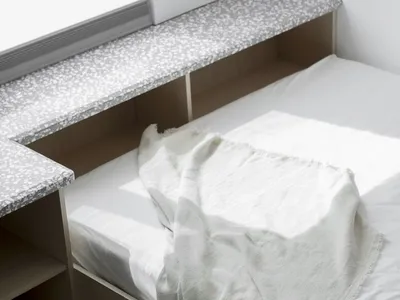 A minimalistic bedroom with a cotton-blend blanket draped over the bed.