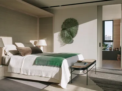 Modern minimalist bedroom with white bed, green throw blanket, and natural light.
