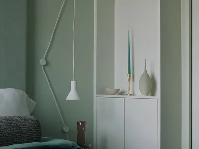 A minimalist bedroom with a blue accent cabinet, white walls, and a simple bed.