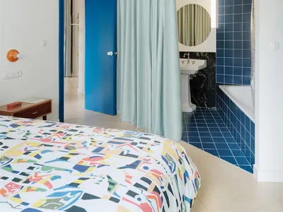 Modern minimalist bedroom with blue curtains and tile flooring.