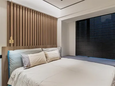 Modern bedroom with a bed featuring fabric bedding and a wooden headboard.