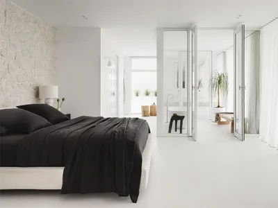 Modern minimalist bedroom featuring a black and white color scheme, with a bed adorned with black bedding against a white wal