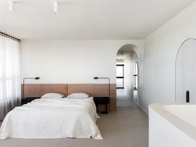 Modern minimalist bedroom featuring a wooden headboard and white bedding