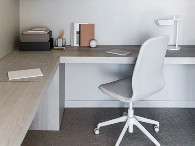 Modern home office featuring a wooden desk and chair, with built-in shelves and cabinets.
