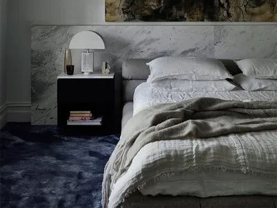 Minimalist-style bedroom featuring a grey bed, white furniture, and a black side table.