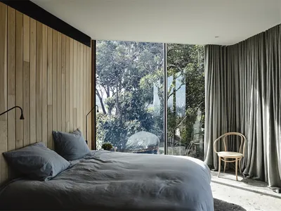 Minimalist bedroom featuring a bed with wood paneling, glass windows, and a gray fabric headboard.