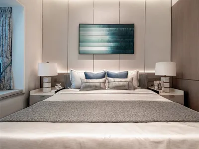A modern minimalist bedroom featuring a large bed with neutral-colored bedding, light wood headboard, and blue abstract paint