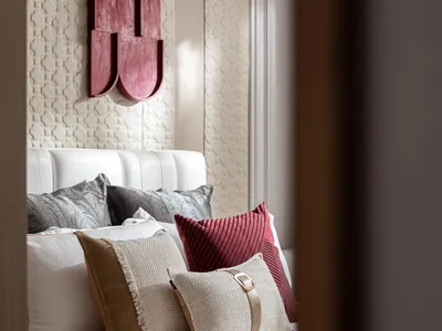 A modern bedroom with a brown color scheme and a variety of pillows on the bed.